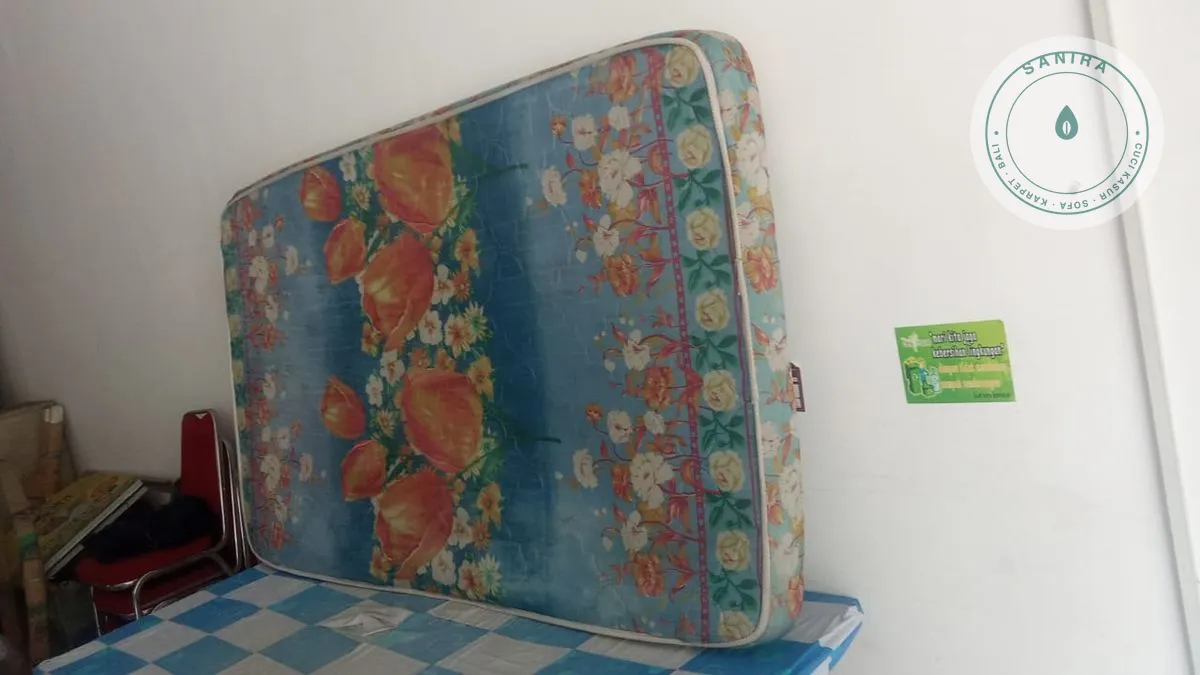 Kasur busa bermotif bunga disandarkan ke tembok di dalam ruangan