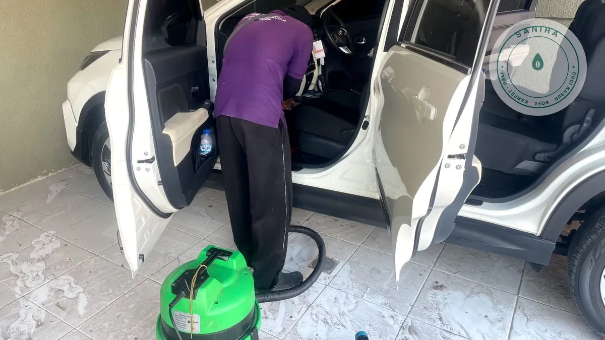 Teknisi Sanira memvakum jok mobil kain di lokasi pelanggan