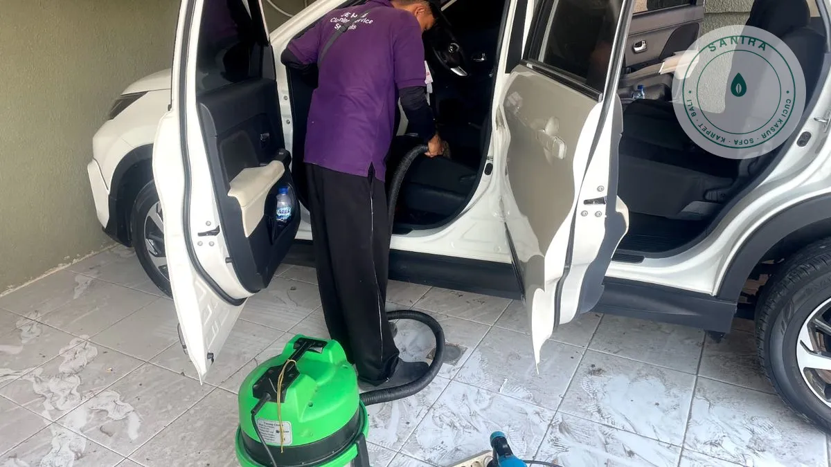 Teknisi Sanira membersihkan jok mobil dengan mesin extraction di lokasi pelanggan