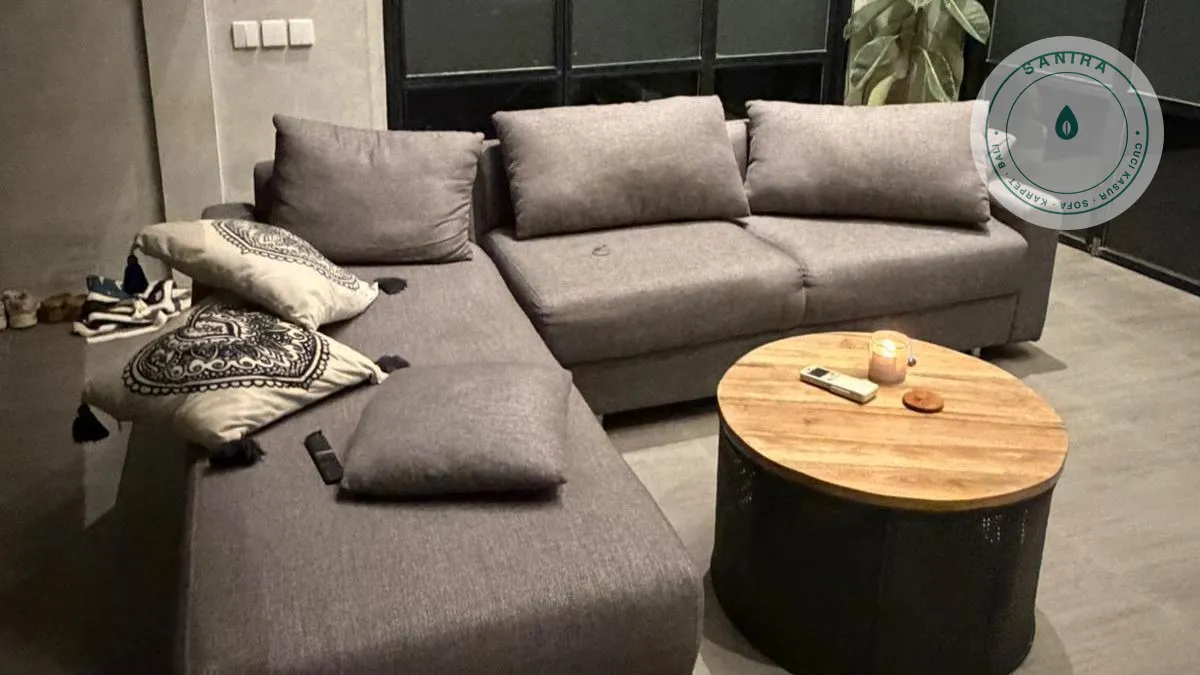 Sofa sectional abu-abu tua di ruang tamu, tertata rapi dengan bantal