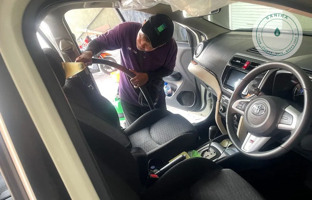 Teknisi Sanira membersihkan jok mobil menggunakan mesin ekstraksi di lokasi pelanggan di Bali